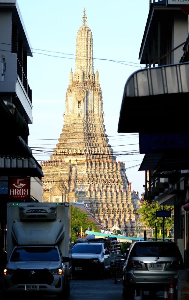 The central prang of Wat Arun, the Temple of Dawn, seen down a Tha Tien street in Bangkok in morning light