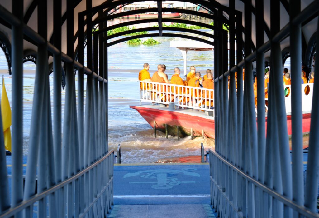 A ferry full of monks in orange robes crossing the Chao Phraya river from Tha Tien pier to Wat Arun