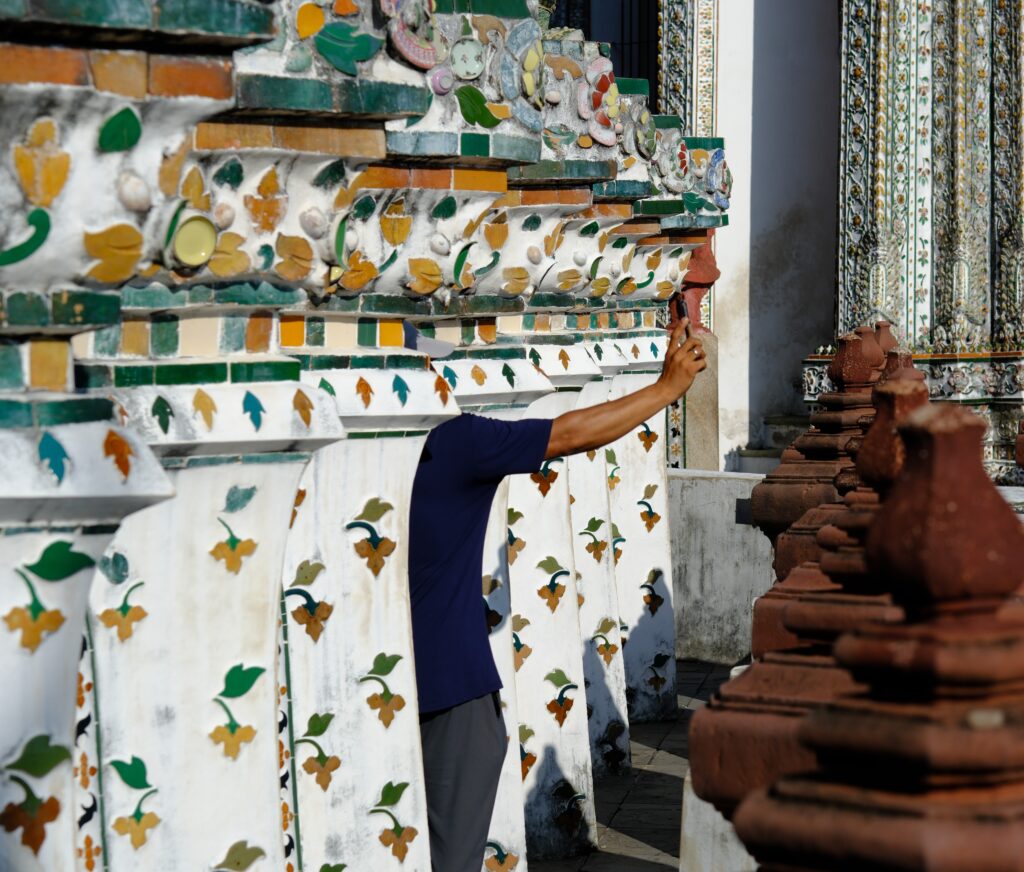 A visitor photographing the porcelain flower mosaic on the base of the Wat Arun prang, made from broken Chinese ceramics