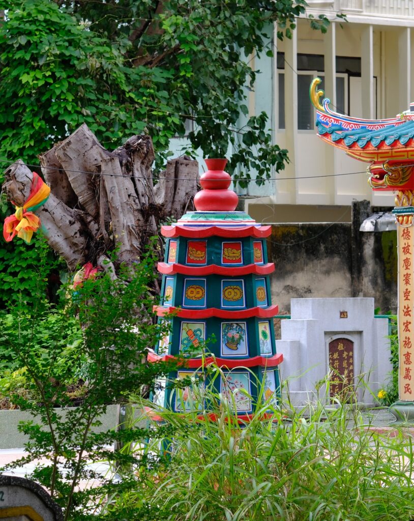Painted pagoda tower with auspicious symbols among graves in Teochew Cemetery Park